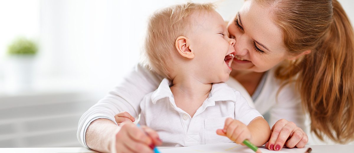 Mother with the baby son with colored pencils and laugh