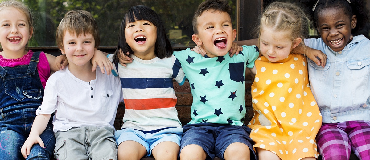 Group of kindergarten kids friends arm around sitting and smiling fun