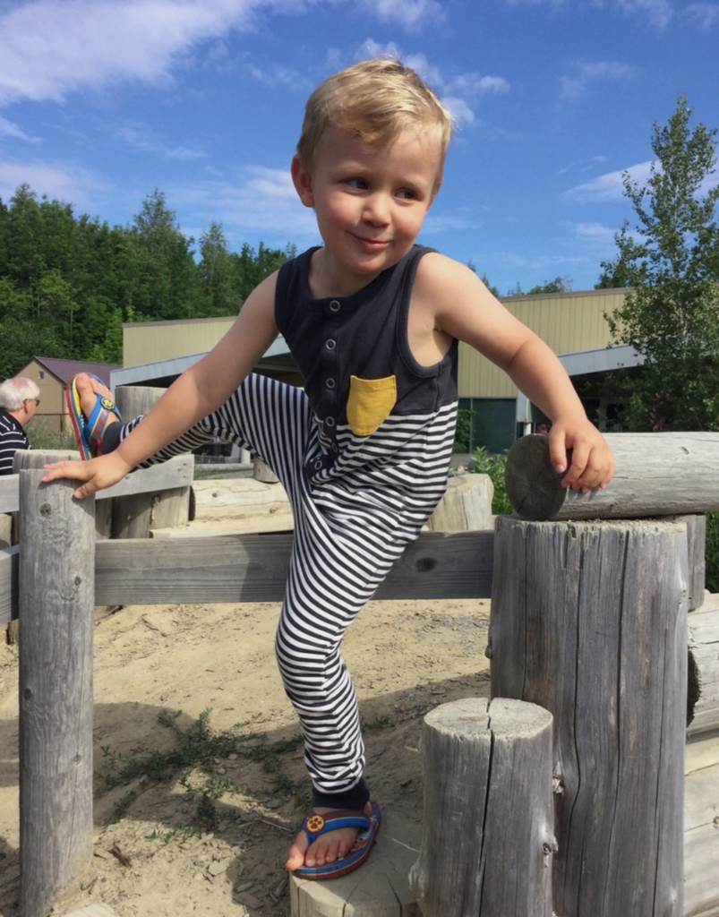 Little boy climbing wooden fence