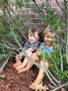 Boy and girl hiding behind bushes
